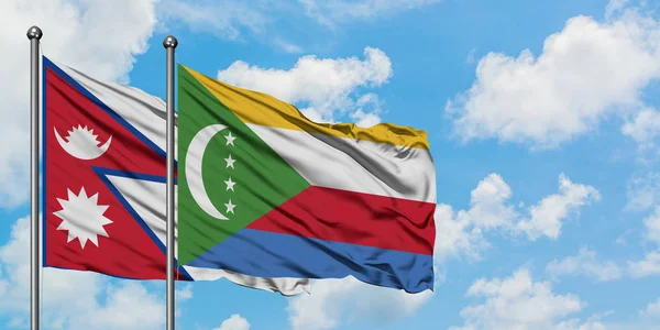 Bandera de Nepal y Comoras ondeando en el viento contra el cielo azul nublado blanco juntos. Concepto diplomático, relaciones internacionales . — Foto de Stock