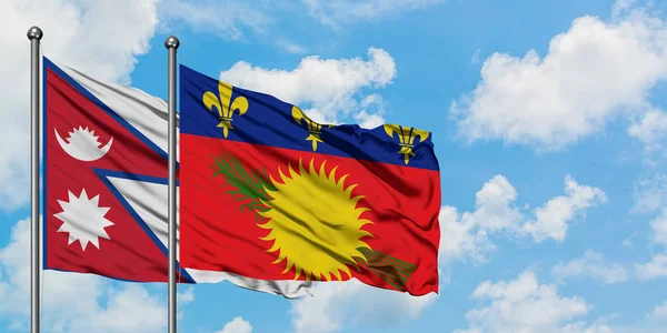 Bandera de Nepal y Guadalupe ondeando en el viento contra el cielo azul nublado blanco juntos. Concepto diplomático, relaciones internacionales . — Foto de Stock