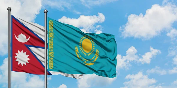 Bandera de Nepal y Kazajstán ondeando en el viento contra el cielo azul nublado blanco juntos. Concepto diplomático, relaciones internacionales . — Foto de Stock