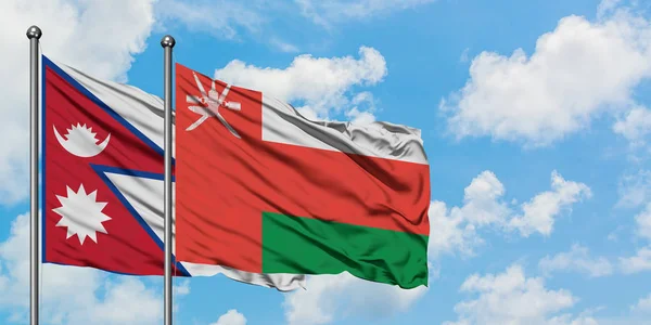 Bandera de Nepal y Omán ondeando en el viento contra el cielo azul nublado blanco juntos. Concepto diplomático, relaciones internacionales . — Foto de Stock