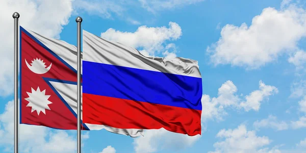 Nepal i Rosja flaga machając w wiatr przed białym zachmurzone błękitne niebo razem. Koncepcja dyplomacji, stosunki międzynarodowe. — Zdjęcie stockowe