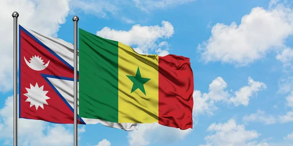 Bandera de Nepal y Senegal ondeando en el viento contra el cielo azul nublado blanco juntos. Concepto diplomático, relaciones internacionales . — Foto de Stock