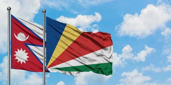 Bandera de Nepal y Seychelles ondeando en el viento contra el cielo azul nublado blanco juntos. Concepto diplomático, relaciones internacionales . — Foto de Stock
