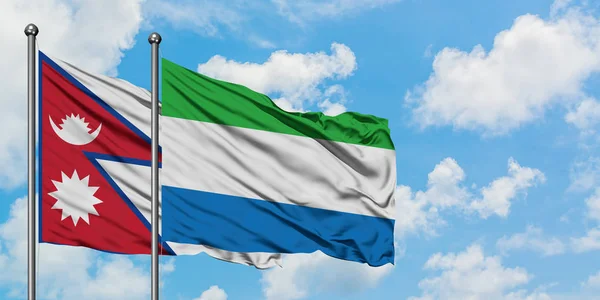 Bandera de Nepal y Sierra Leona ondeando en el viento contra el cielo azul nublado blanco juntos. Concepto diplomático, relaciones internacionales . — Foto de Stock