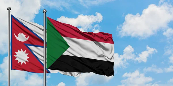 Bandera de Nepal y Sudán ondeando en el viento contra el cielo azul nublado blanco juntos. Concepto diplomático, relaciones internacionales . — Foto de Stock