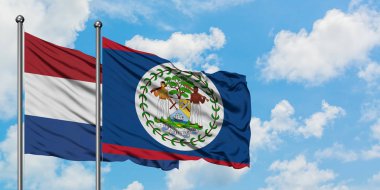 Hollanda ve Belize bayrağı birlikte beyaz bulutlu mavi gökyüzüne karşı rüzgarsal sallayarak. Diplomasi kavramı, uluslararası ilişkiler.