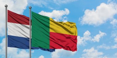 Hollanda ve Benin bayrağı birlikte beyaz bulutlu mavi gökyüzüne karşı rüzgarsal sallayarak. Diplomasi kavramı, uluslararası ilişkiler.