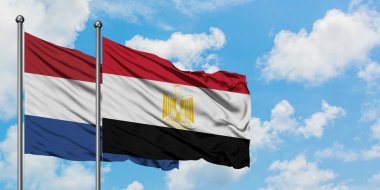 Hollanda ve Mısır bayrağı birlikte beyaz bulutlu mavi gökyüzüne karşı rüzgarsal sallayarak. Diplomasi kavramı, uluslararası ilişkiler.