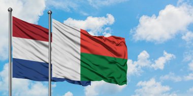 Hollanda ve Madagaskar bayrağı birlikte beyaz bulutlu mavi gökyüzüne karşı rüzgarsal sallayarak. Diplomasi kavramı, uluslararası ilişkiler.