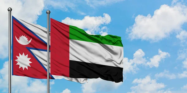 Bandera de Nepal y Emiratos Árabes Unidos ondeando en el viento contra el cielo azul nublado blanco juntos. Concepto diplomático, relaciones internacionales . — Foto de Stock