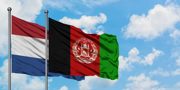 Bandera de Holanda y Afganistán ondeando en el viento contra el cielo azul nublado blanco juntos. Concepto diplomático, relaciones internacionales . — Foto de Stock