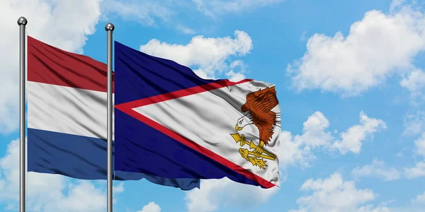 Bandera de los Países Bajos y Samoa Americana ondeando en el viento contra el cielo azul nublado blanco juntos. Concepto diplomático, relaciones internacionales . — Foto de Stock