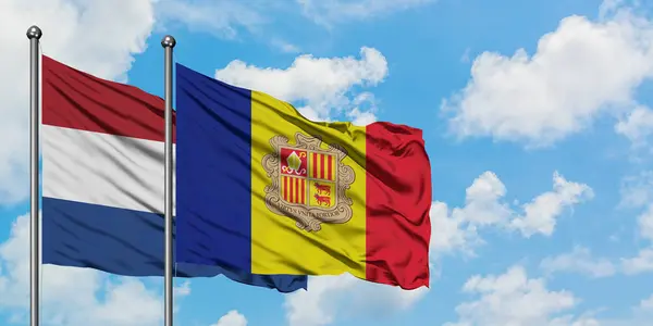 Bandera de Holanda y Andorra ondeando en el viento contra el cielo azul nublado blanco juntos. Concepto diplomático, relaciones internacionales . — Foto de Stock