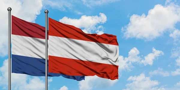 Нідерланди і Австрія прапор розмахуючи в вітру проти білого хмарного синього неба разом. Концепція дипломатії, міжнародні відносини. — стокове фото