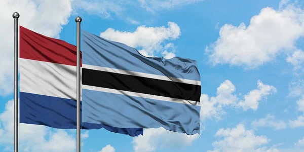 荷兰和博茨瓦纳国旗在风中飘扬，与白云蓝天相一起。外交概念、国际关系. — 图库照片