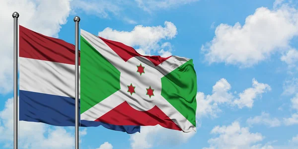 Holanda e Burundi acenando com o vento contra o céu azul nublado branco juntos. Conceito de diplomacia, relações internacionais . — Fotografia de Stock