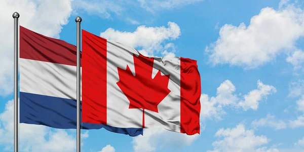 Le drapeau des Pays-Bas et du Canada agitant dans le vent contre le ciel bleu nuageux blanc ensemble. Concept de diplomatie, relations internationales . — Photo