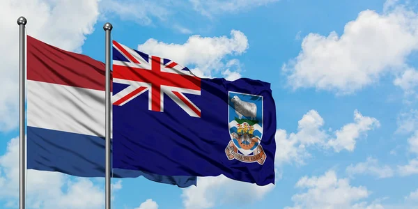 Paesi Bassi e Isole Falkland bandiera sventolando nel vento contro bianco cielo blu nuvoloso insieme. Concetto di diplomazia, relazioni internazionali . — Foto Stock