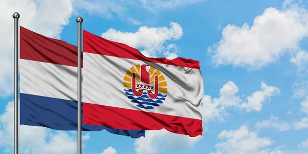 Нідерланди і французькі Полінезії прапор розмахуючи в вітру проти білого хмарного синього неба разом. Концепція дипломатії, міжнародні відносини. — стокове фото