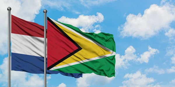 Netherlands and Guyana flag waving in the wind against white cloudy blue sky together. Diplomacy concept, international relations. — Stock Photo, Image