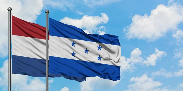 Bandera de Holanda y Honduras ondeando en el viento contra el cielo azul nublado blanco juntos. Concepto diplomático, relaciones internacionales . — Foto de Stock