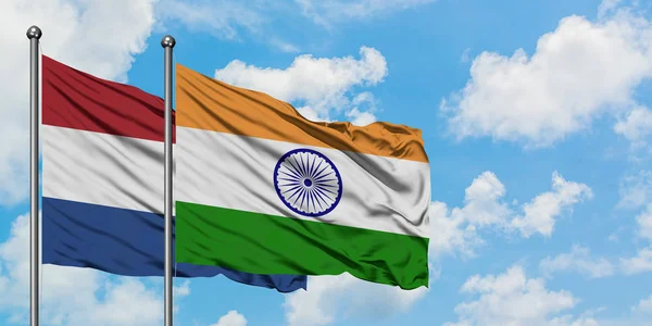 Bandera de los Países Bajos e India ondeando en el viento contra el cielo azul nublado blanco juntos. Concepto diplomático, relaciones internacionales . — Foto de Stock