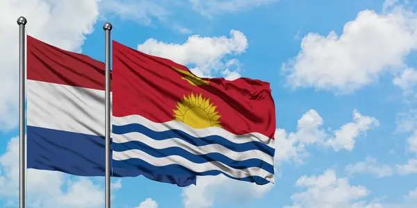 Bandera de Holanda y Kiribati ondeando en el viento contra el cielo azul nublado blanco juntos. Concepto diplomático, relaciones internacionales . — Foto de Stock