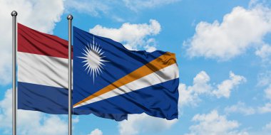 Hollanda ve Marshall Adaları bayrağı birlikte beyaz bulutlu mavi gökyüzüne karşı rüzgarsal sallayarak. Diplomasi kavramı, uluslararası ilişkiler.