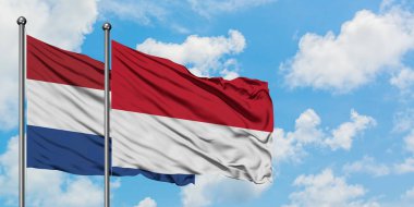 Hollanda ve Monako bayrağı birlikte beyaz bulutlu mavi gökyüzüne karşı rüzgarsal sallayarak. Diplomasi kavramı, uluslararası ilişkiler.