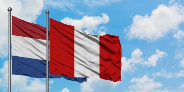 Hollanda ve Peru bayrağı birlikte beyaz bulutlu mavi gökyüzüne karşı rüzgarsal sallayarak. Diplomasi kavramı, uluslararası ilişkiler.