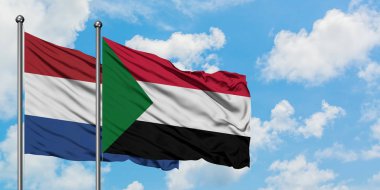 Hollanda ve Sudan bayrağı birlikte beyaz bulutlu mavi gökyüzüne karşı rüzgarsal sallayarak. Diplomasi kavramı, uluslararası ilişkiler.
