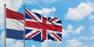 Hollanda ve Birleşik Krallık bayrağı birlikte beyaz bulutlu mavi gökyüzüne karşı rüzgarsal sallayarak. Diplomasi kavramı, uluslararası ilişkiler.