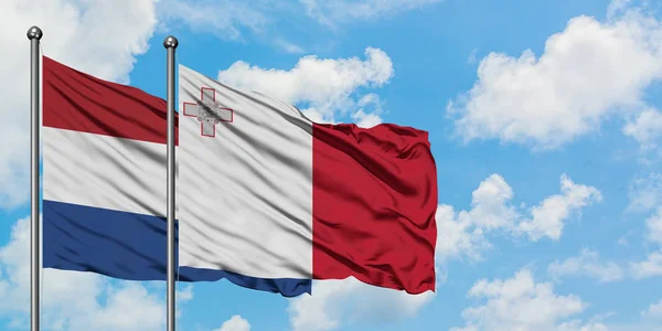 Netherlands and Malta flag waving in the wind against white cloudy blue sky together. Diplomacy concept, international relations.