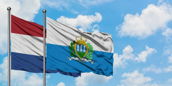Голландія і Сан-Марино прапора розмахуючи в вітру проти білого хмарного синього неба разом. Концепція дипломатії, міжнародні відносини. — стокове фото