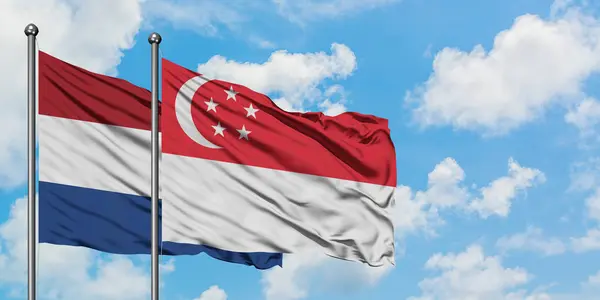 Netherlands and Singapore flag waving in the wind against white cloudy blue sky together. Diplomacy concept, international relations. — Stock Photo, Image