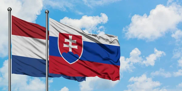 Nederländerna och Slovakien flagga vifta i vinden mot vit grumlig blå himmel tillsammans. Diplomatisk koncept, internationella relationer. — Stockfoto