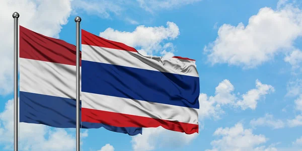 Bandera de los Países Bajos y Tailandia ondeando en el viento contra el cielo azul nublado blanco juntos. Concepto diplomático, relaciones internacionales . — Foto de Stock