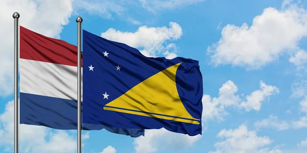 Holanda e Tokelau bandeira acenando no vento contra o céu azul nublado branco juntos. Conceito de diplomacia, relações internacionais . — Fotografia de Stock