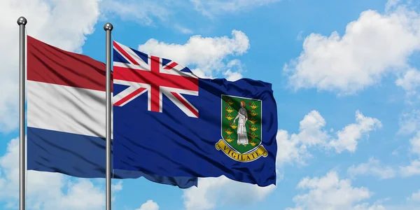 Bandera de los Países Bajos y las Islas Vírgenes Británicas ondeando en el viento contra el cielo azul nublado blanco juntos. Concepto diplomático, relaciones internacionales . — Foto de Stock