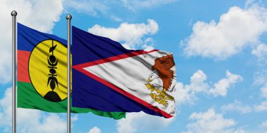 Yeni Kaledonya ve Amerikan Samoa bayrağı birlikte beyaz bulutlu mavi gökyüzüne karşı rüzgarda sallayarak. Diplomasi kavramı, uluslararası ilişkiler.
