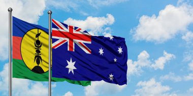 Yeni Kaledonya ve Avustralya bayrağı birlikte beyaz bulutlu mavi gökyüzüne karşı rüzgarda sallayarak. Diplomasi kavramı, uluslararası ilişkiler.