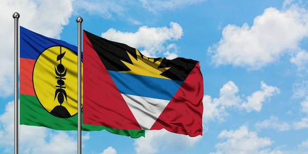 New Caledonia and Antigua and Barbuda flag waving in the wind against white cloudy blue sky together. Diplomacy concept, international relations. — Stock Photo, Image