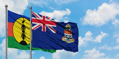 Yeni Kaledonya ve Cayman Adaları bayrağı birlikte beyaz bulutlu mavi gökyüzüne karşı rüzgarda sallayarak. Diplomasi kavramı, uluslararası ilişkiler.