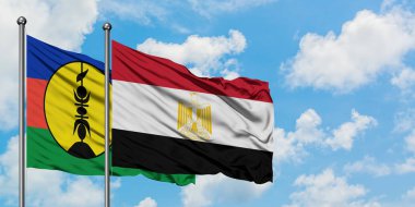 Yeni Kaledonya ve Mısır bayrağı birlikte beyaz bulutlu mavi gökyüzüne karşı rüzgarda sallayarak. Diplomasi kavramı, uluslararası ilişkiler.