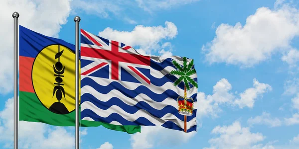 Új-Kaledónia és a brit indiai-óceáni terület zászló integetett a szél ellen, fehér felhős kék ég együtt. Diplomáciai koncepció, nemzetközi kapcsolatok. — Stock Fotó