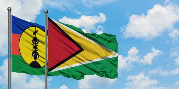 Nuova Caledonia e Guyana sventolano nel vento contro il bianco cielo azzurro nuvoloso insieme. Concetto di diplomazia, relazioni internazionali . — Foto Stock