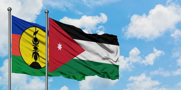 Bandera de Nueva Caledonia y Jordania ondeando en el viento contra el cielo azul nublado blanco juntos. Concepto diplomático, relaciones internacionales . — Foto de Stock