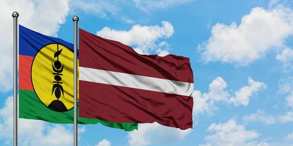 Nowa Kaledonia i Łotwa flaga machając w wiatr przed białym zachmurzone błękitne niebo razem. Koncepcja dyplomacji, stosunki międzynarodowe. — Zdjęcie stockowe