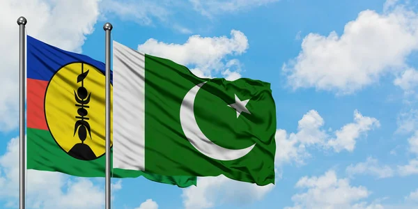 Bandera de Nueva Caledonia y Pakistán ondeando en el viento contra el cielo azul nublado blanco juntos. Concepto diplomático, relaciones internacionales . — Foto de Stock