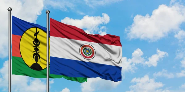 Bandera de Nueva Caledonia y Paraguay ondeando en el viento contra el cielo azul nublado blanco juntos. Concepto diplomático, relaciones internacionales . — Foto de Stock